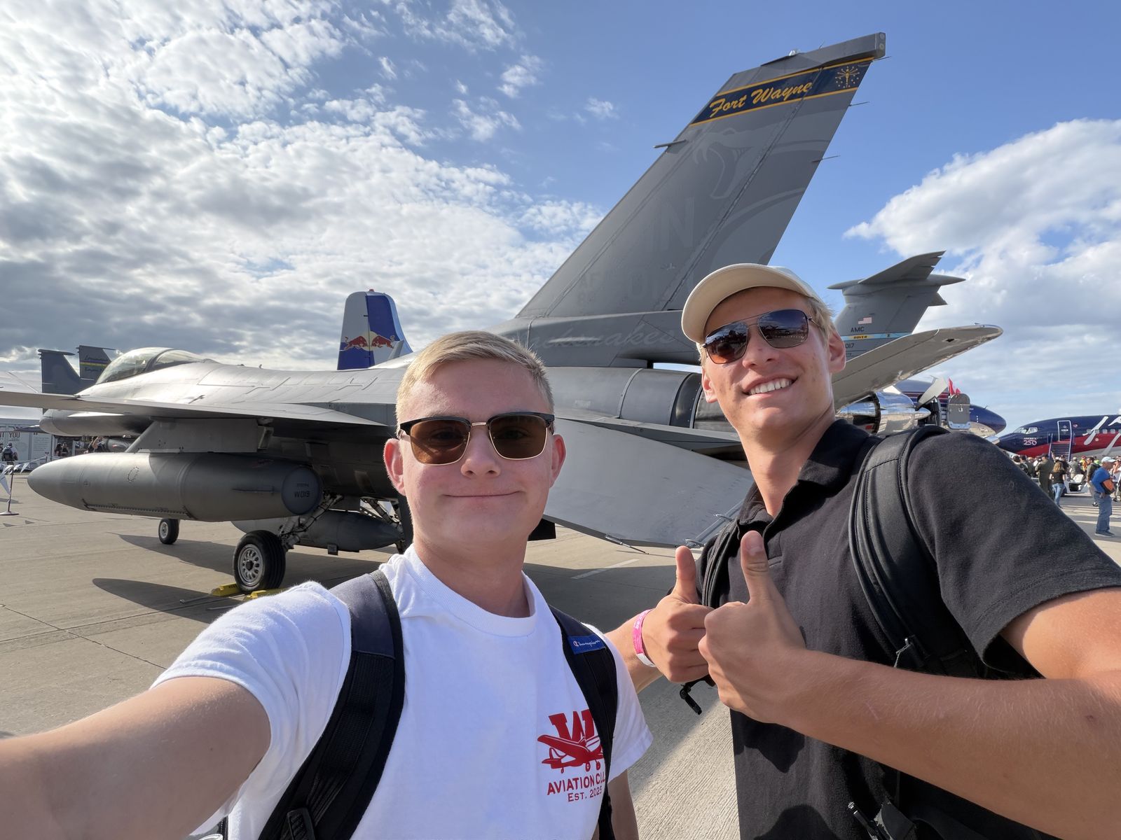 Two club members take a selfie in front of an F-16 at EAA AirVenture Oshkosh