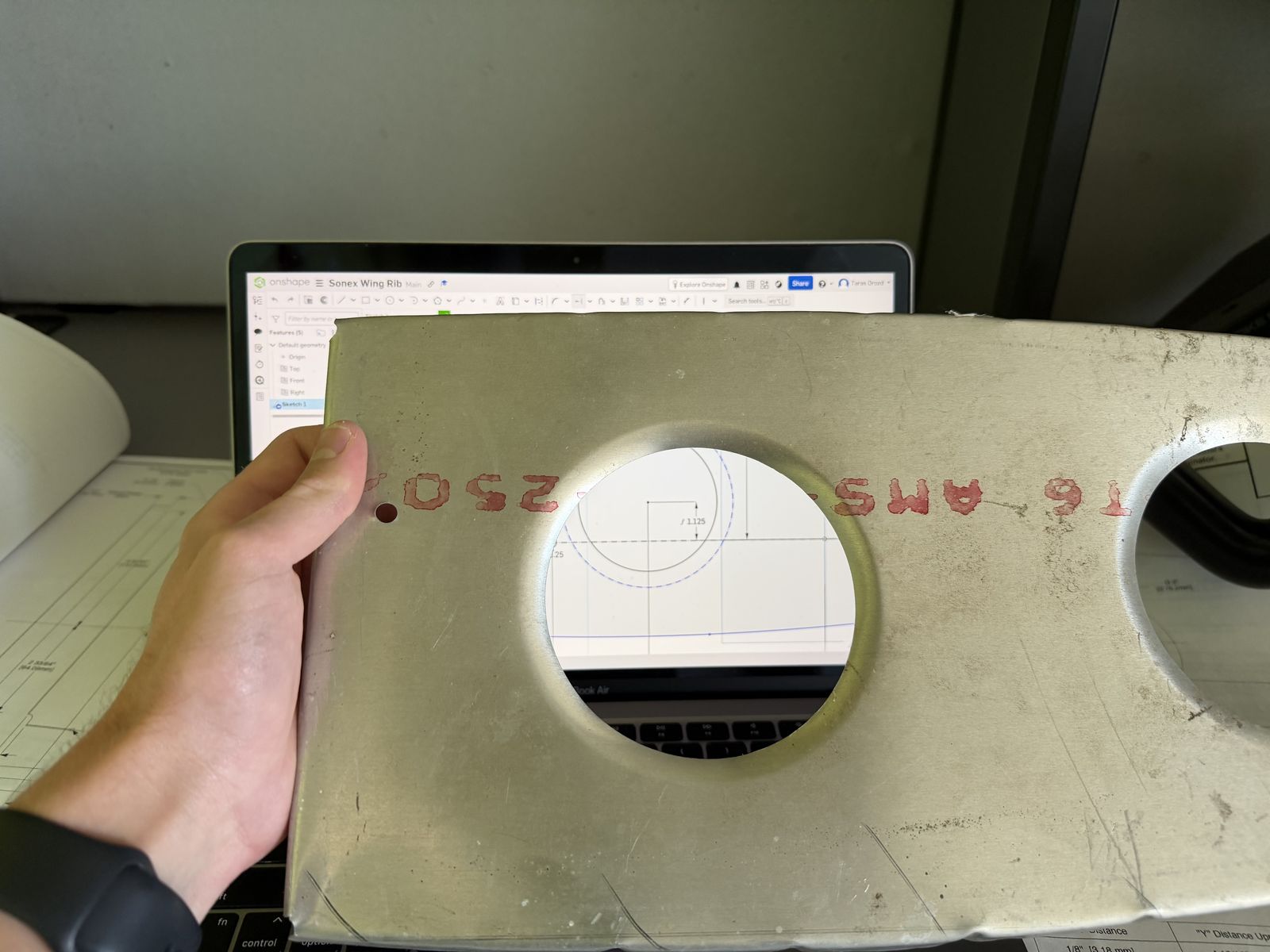 Aluminum Sonex wing rib held up in front of its CAD drawing on a laptop